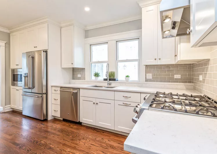Bright open kitchen with white cabinets stainless steel appliances and hardwood floors