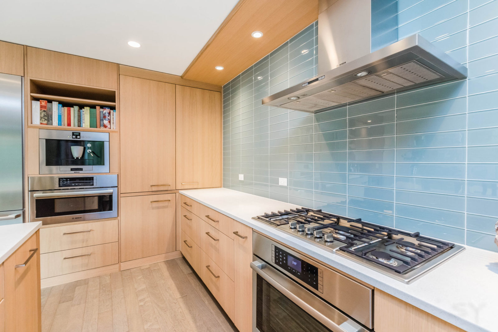 livco kitchen renovation light wood cabinetry light blue subway tile backsplash hooded vent