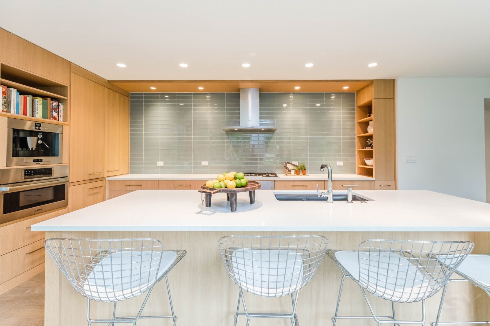 kitchen with large island white countertops and bar seating subway tile backsplash and hooded vent