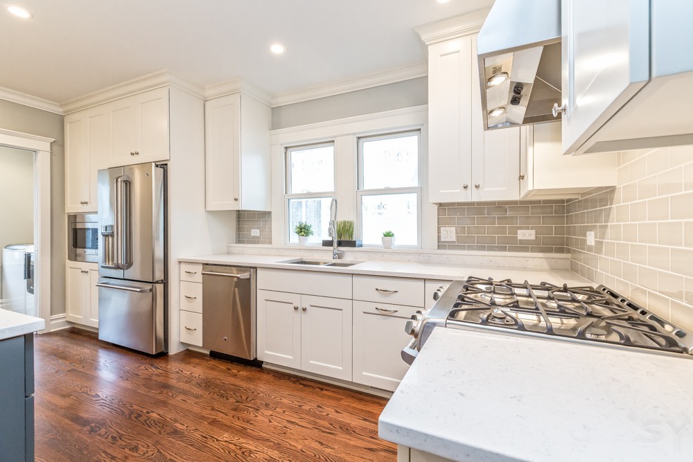 bright airy kitchen white cabinets and countertops stainless steel appliances hardwood floors