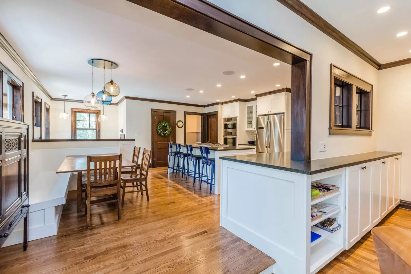 Bright Open Kitchen with bench style dining seating large island white cabinets wooden crown molding