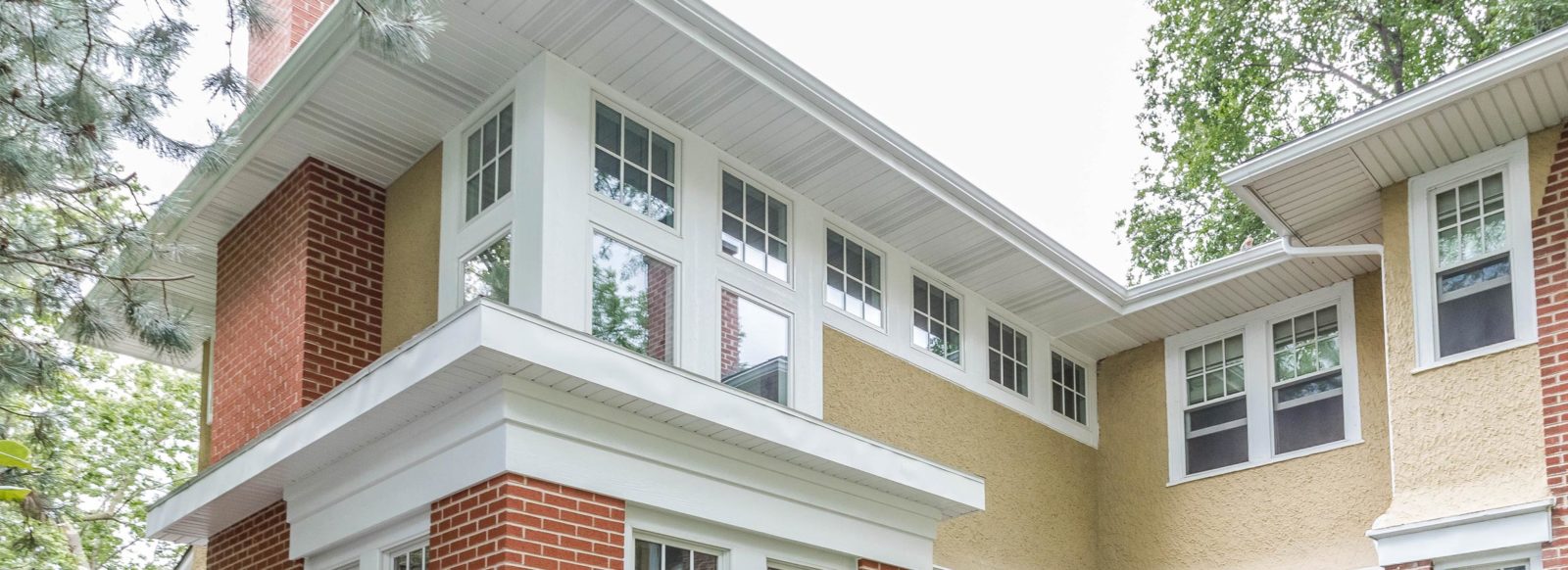 Exterior of the second story of a home with brick and beige stucco and lots of windows