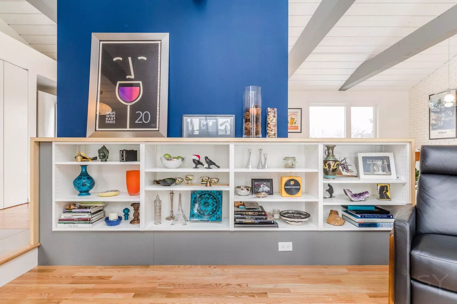 LivCo living room remodel open shelving housing keepsakes and eclectic artwork blue wall