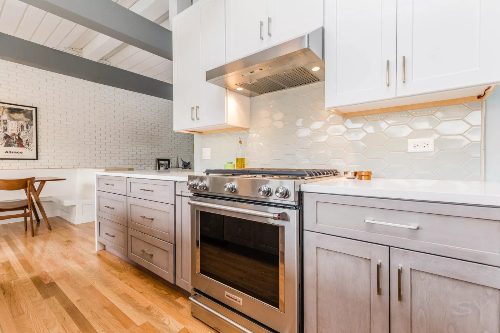 kitchen remodel grey cabinets below white above hexagon backsplash tile gas stove