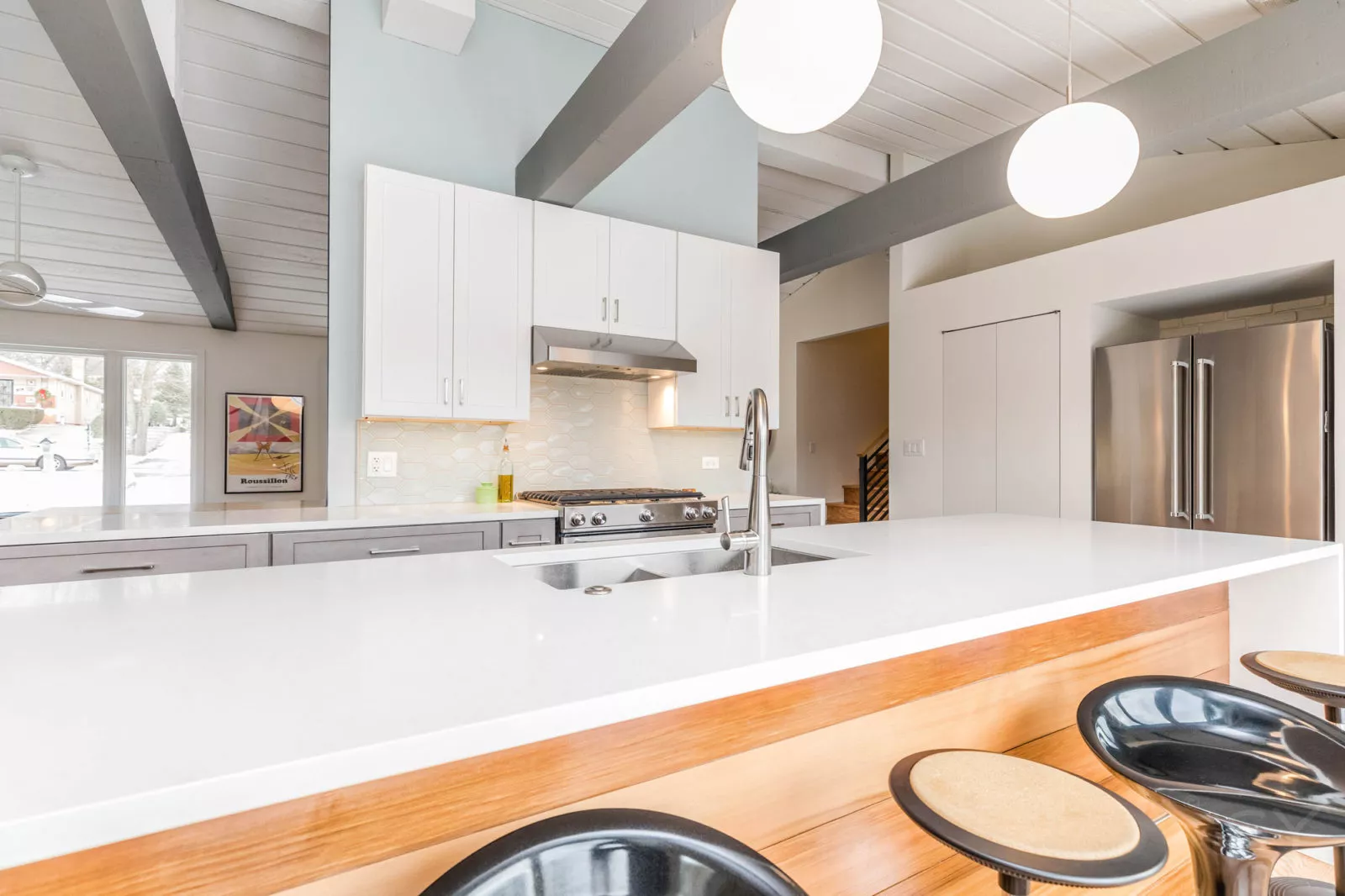 white cabinets & countertops stainless steel appliances grey ceiling beams & large white island