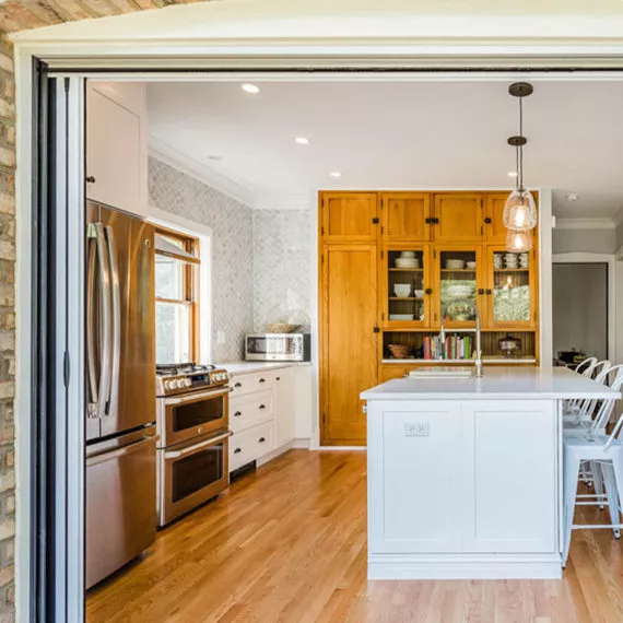 view of vintage kitchen remodel from deck showing folding glass door and pine buffet cabinet