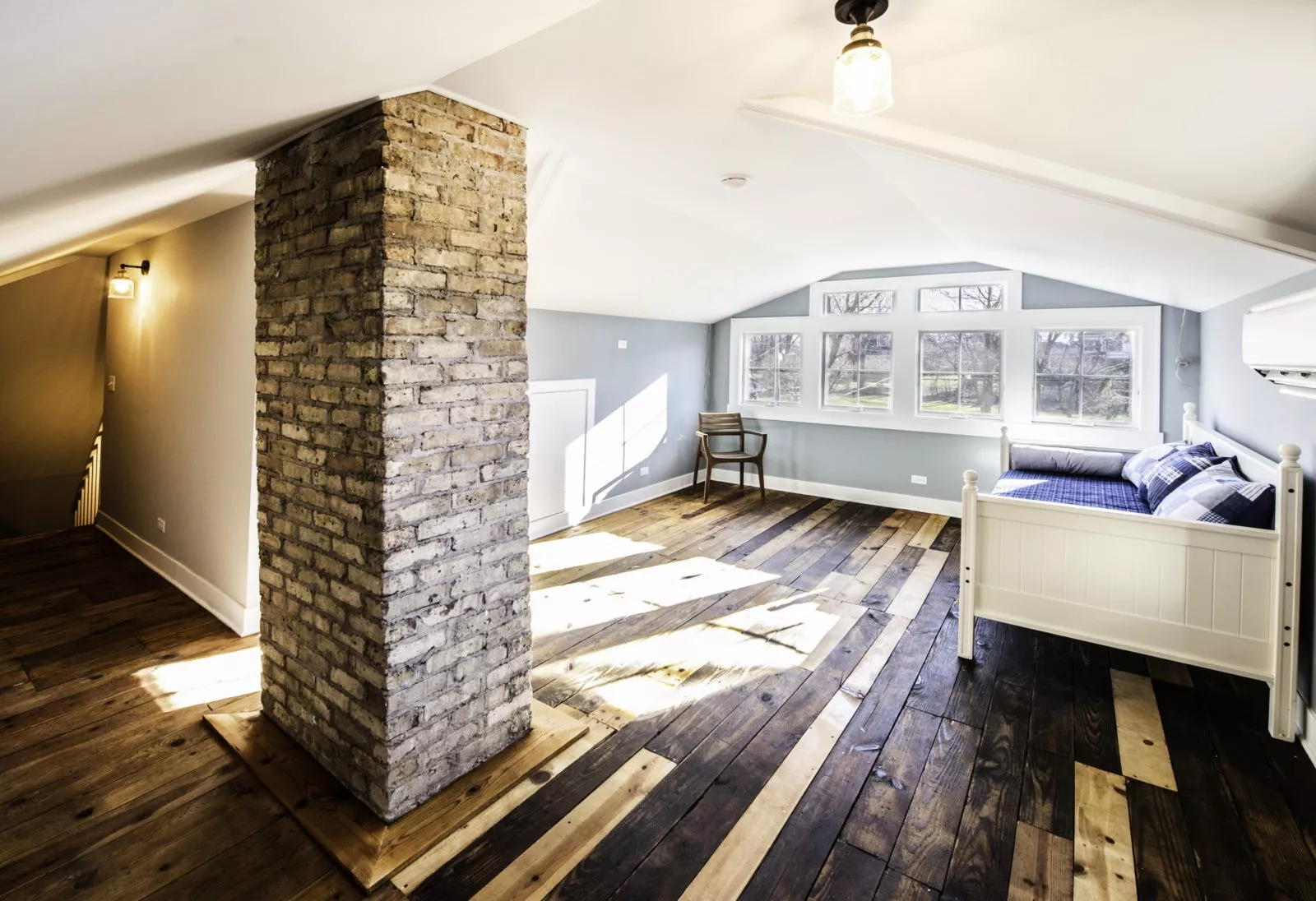 Attic renovation with light blue walls hardwood floors and a brick chimnney as the centerpiece