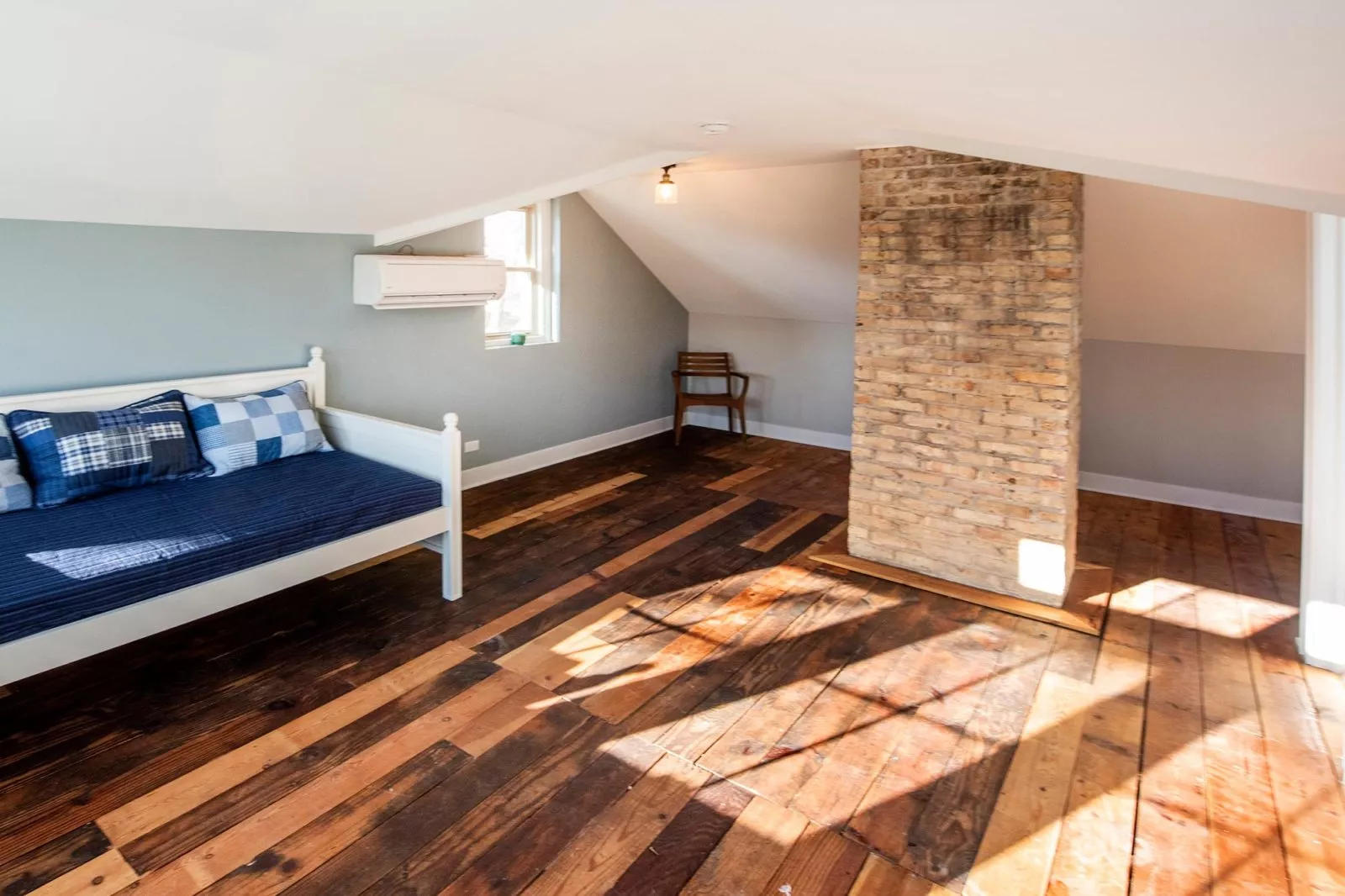 Updated second-story bonus space with multi-toned wood flooring, original brick chimney, & daybed