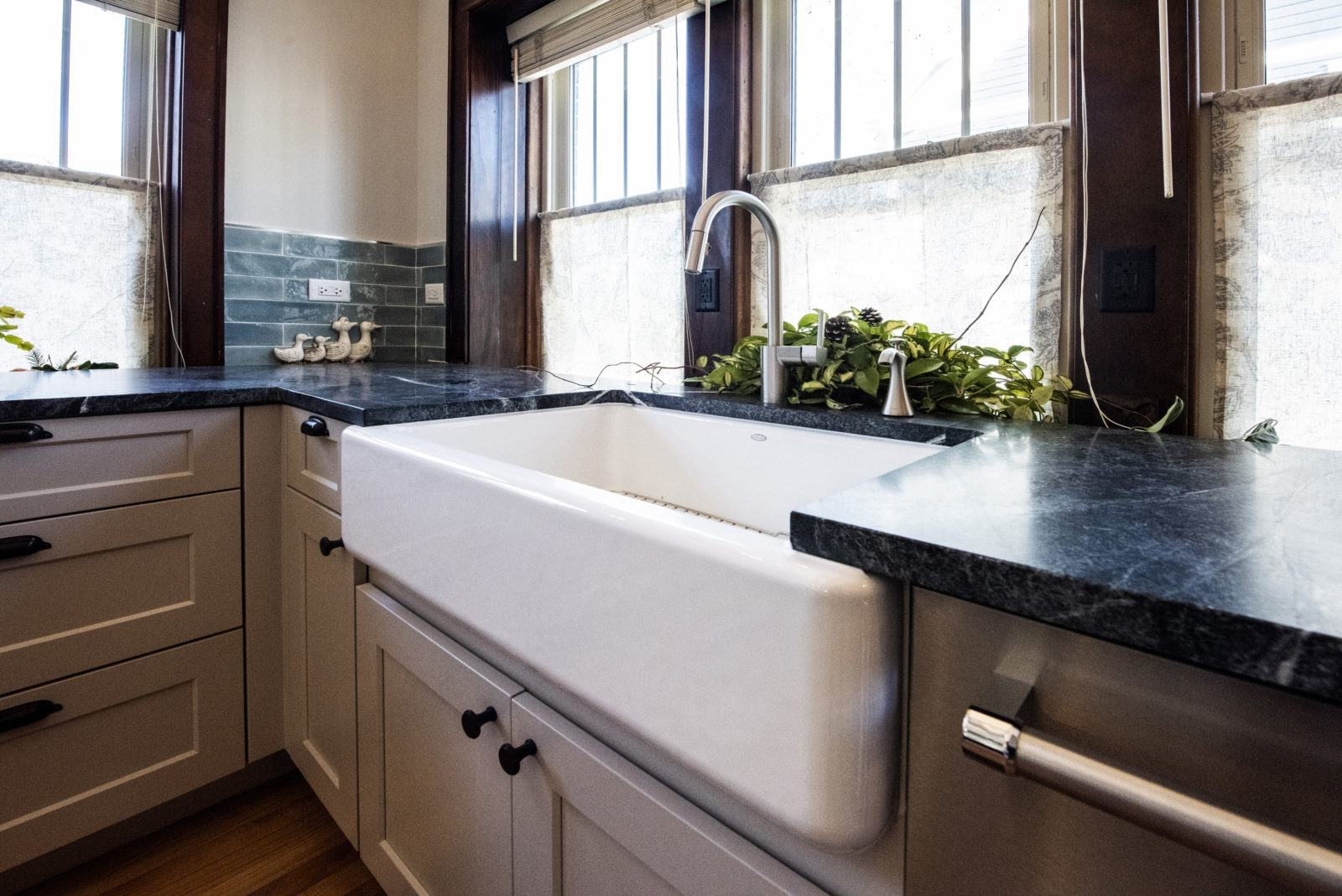 Close-up of tub-style white sink, black granite countertops in a kitchen