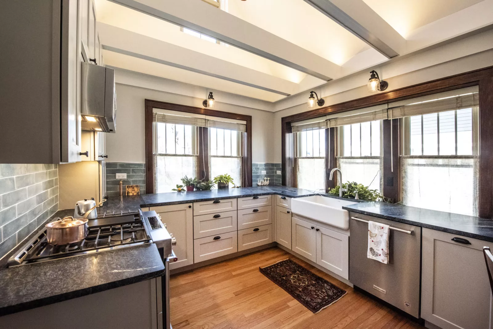 Cozy kitchen with grey cabinets & drawers, black granite countertops, silver appliances, 5 windows