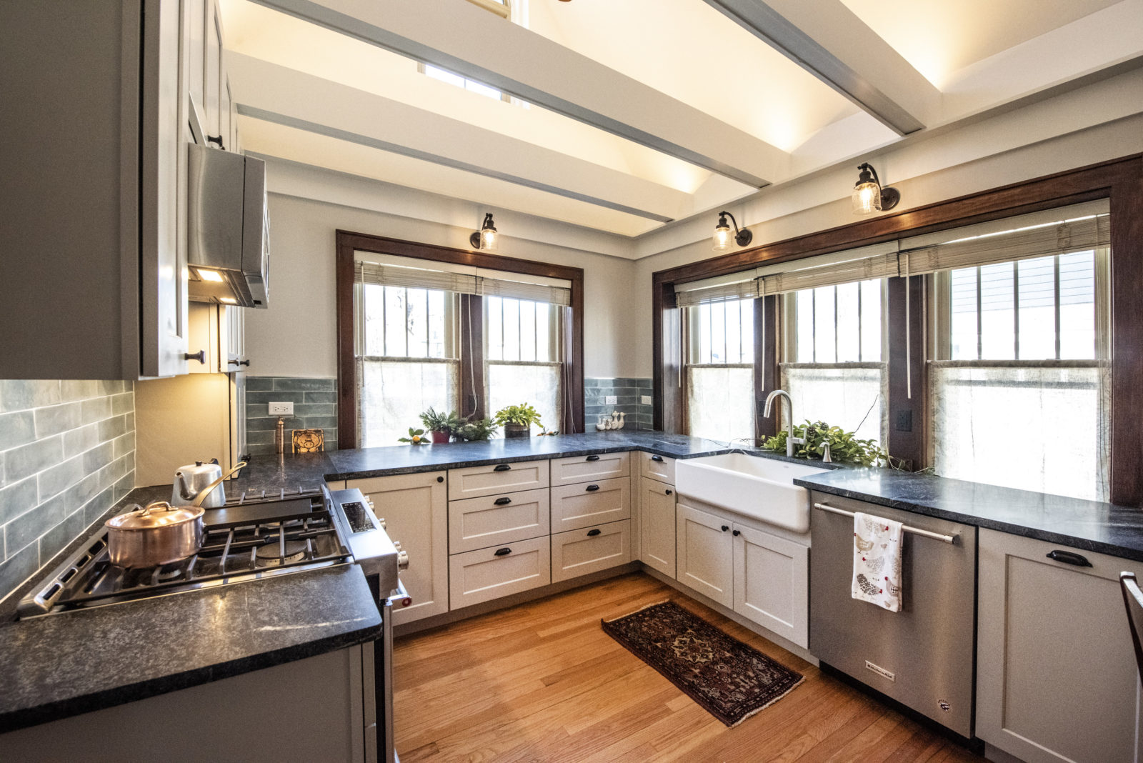 Cozy kitchen with grey cabinets & drawers, black granite countertops, silver appliances, 5 windows