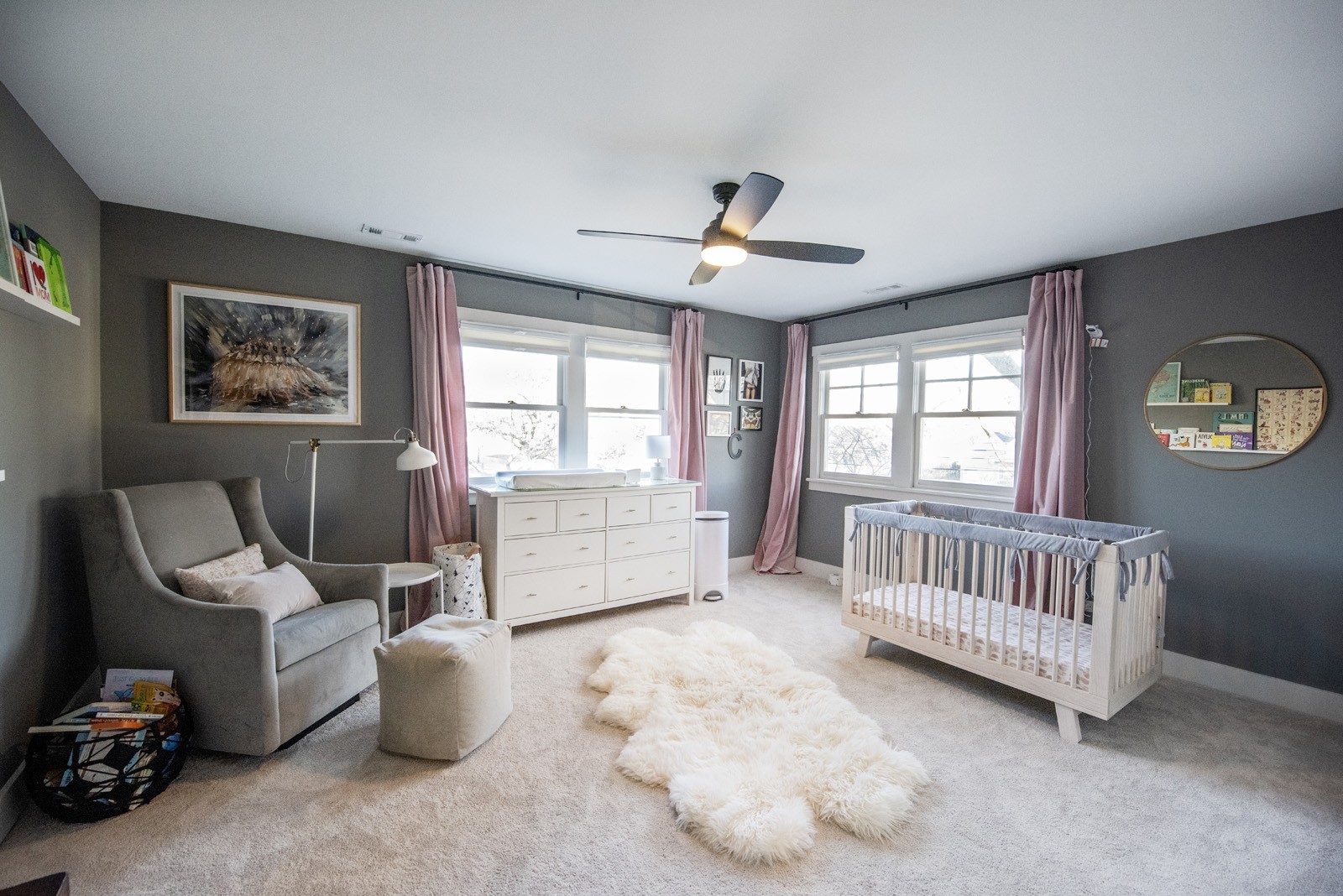 nursery renovation grey walls open pink drapes grey velvet sitting chair white crib fluffy rug