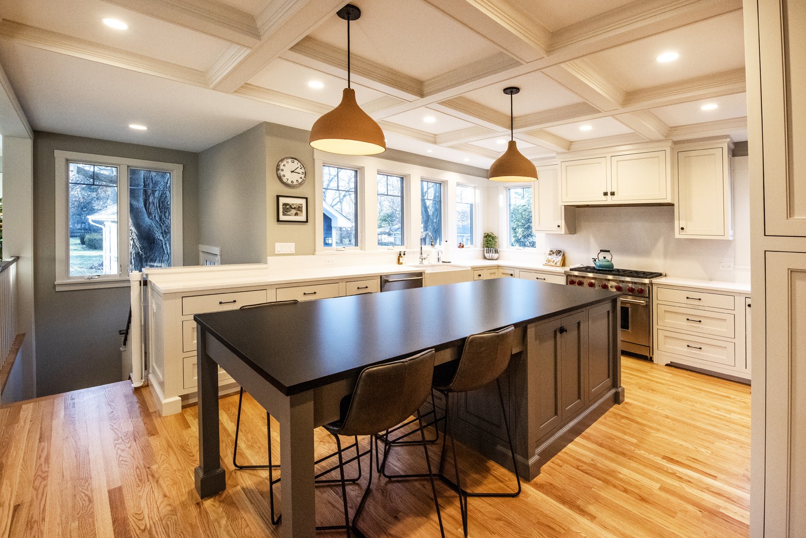 kitchen with white cabinets light hardwood floors grey walls large dark island table combination