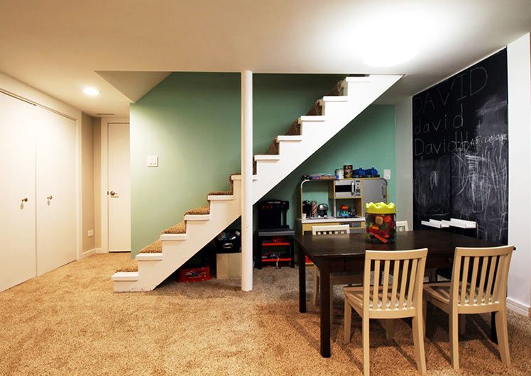 basement with green accent wall chalkboard wall black table with chairs and carpeted floors