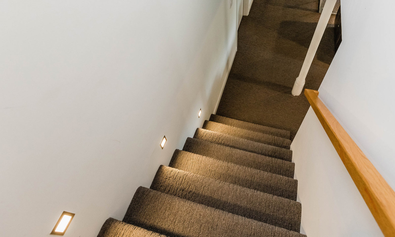 mid century modern ranch renovation and remodel view of carpeted and lighted stairs to basement