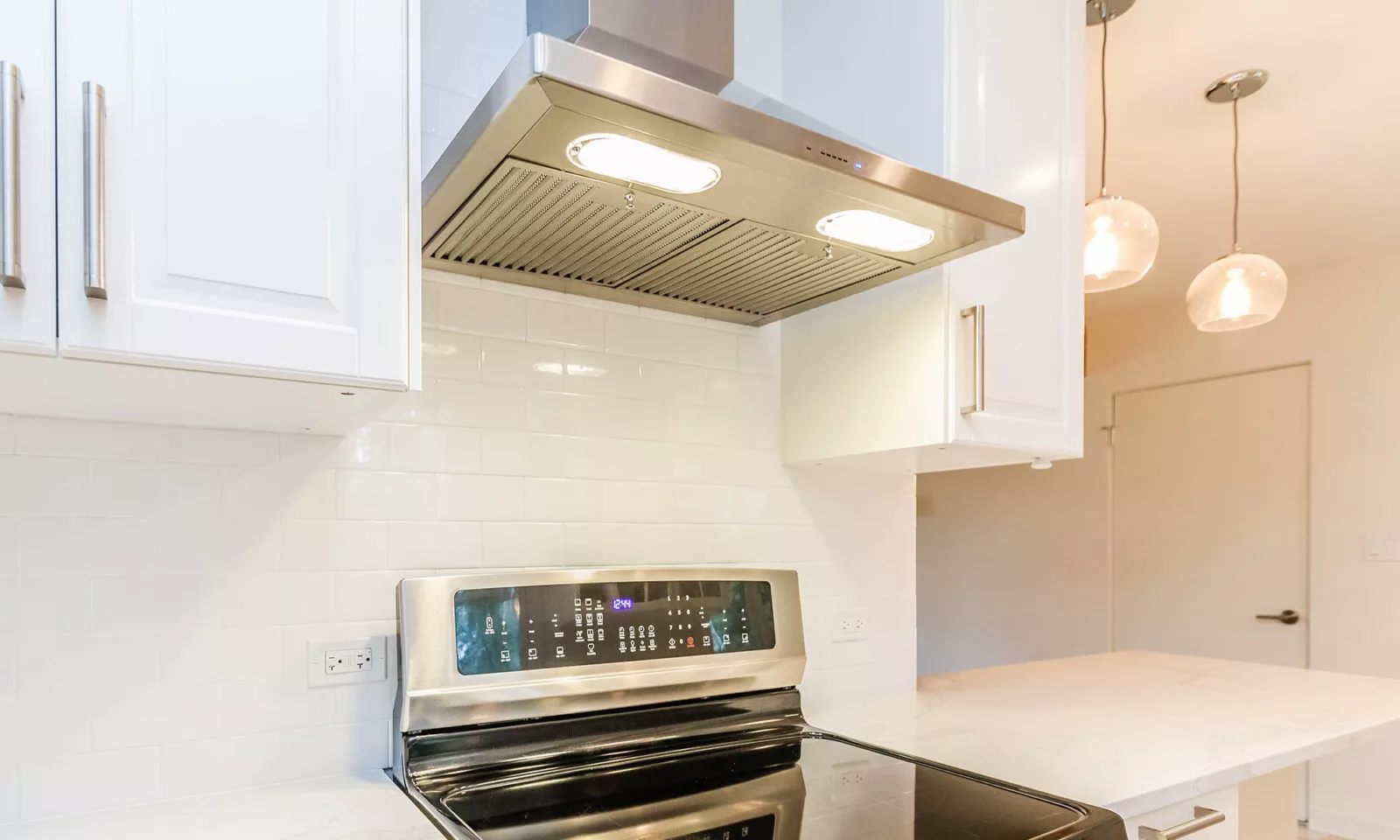 mid century modern ranch renovation and remodel view of white kithcen with stainless steel appliances range and hood