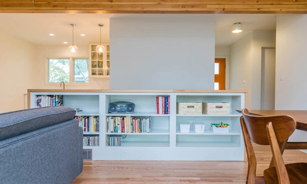 mid century modern renovation view of open shelves dividing family room from basement stair