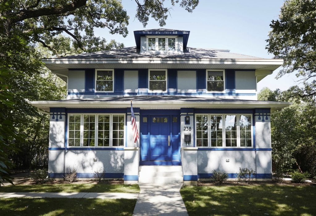 two story grey home with blue front door shutters and accents with american flag hunt next to door