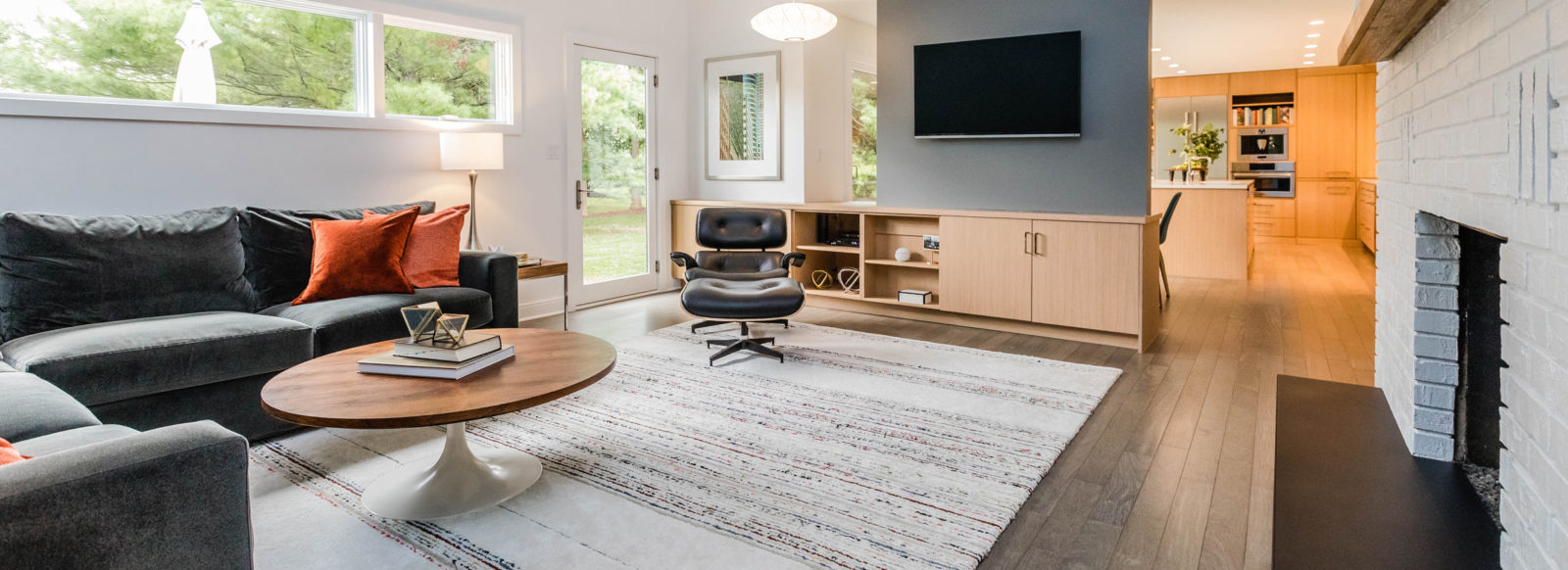 Bright Airy Modern Remodeled Living Room Kitchen Space Orange pillows sit on grey velvet couch