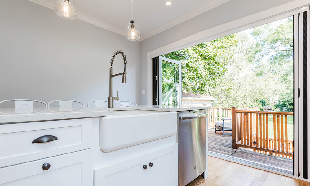 kitchen remodel with folding galss doors to the deck open with accordion screen and farmhouse sink