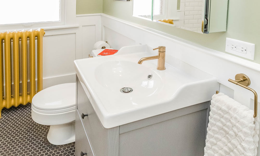 vintage bathroom remodel with grey vanity and red reading glasses on the commode