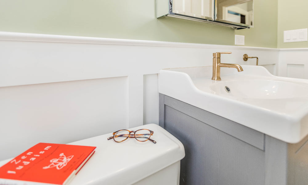 vintage bathroom remodel with grey vanity and red reading glasses on the commode