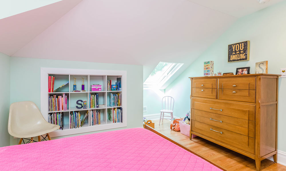 girls bedroom with pink comforter and built-in wall storage