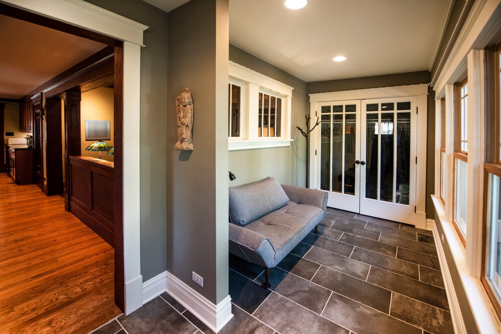 Sitting area with couch and closet with glass doors, adjacent to kitchen with wood floors