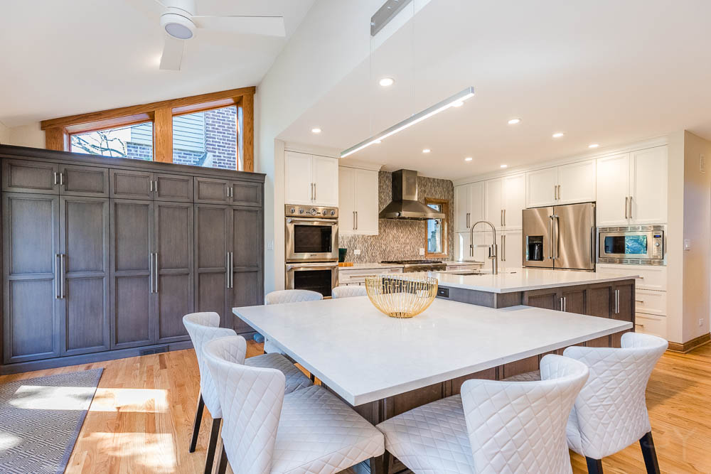 Modern dining room & kitchen with island table, chairs and appliances