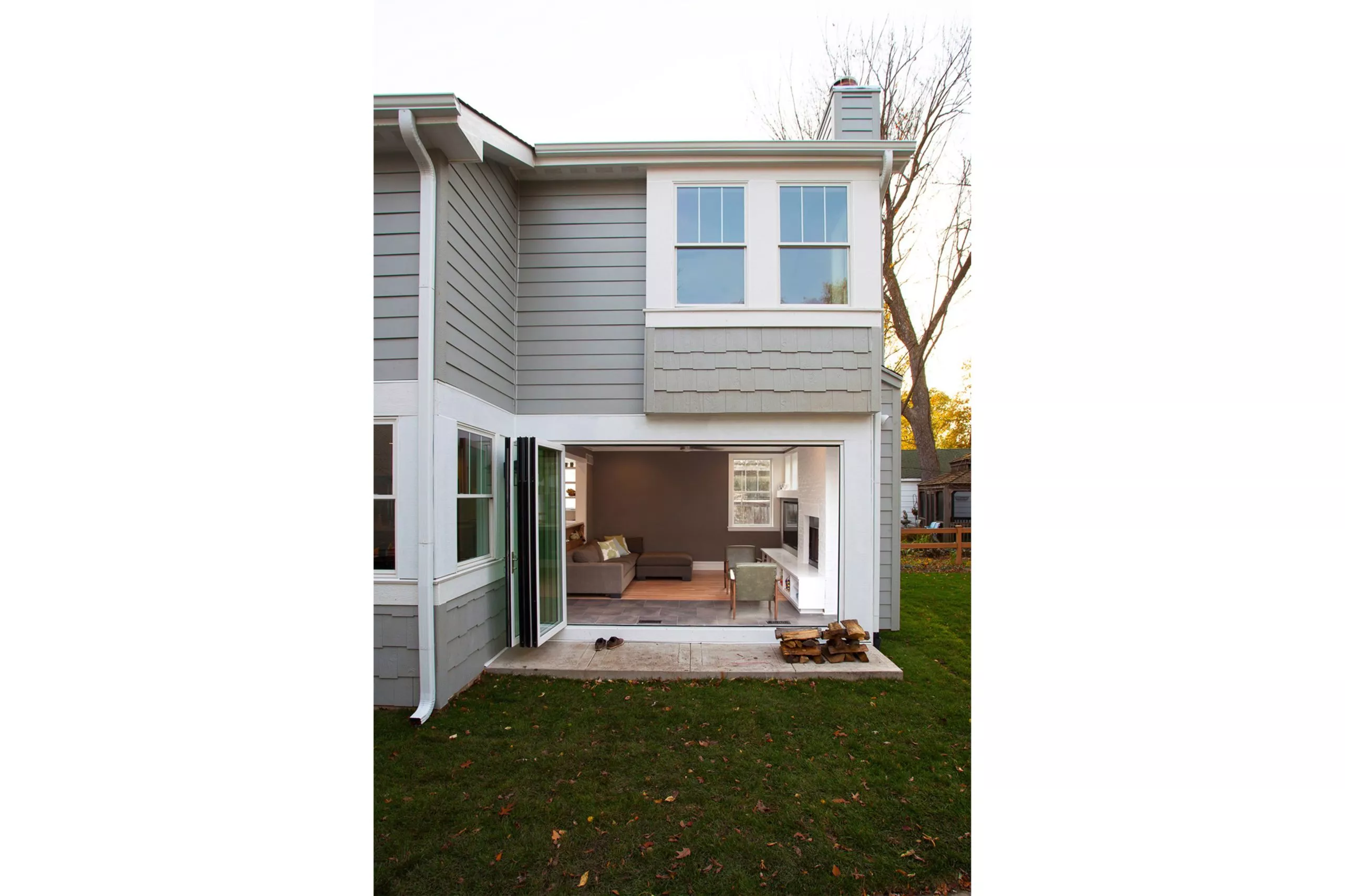Exterior of a grey-sided house looking through a doorway into a living room with couch and TV