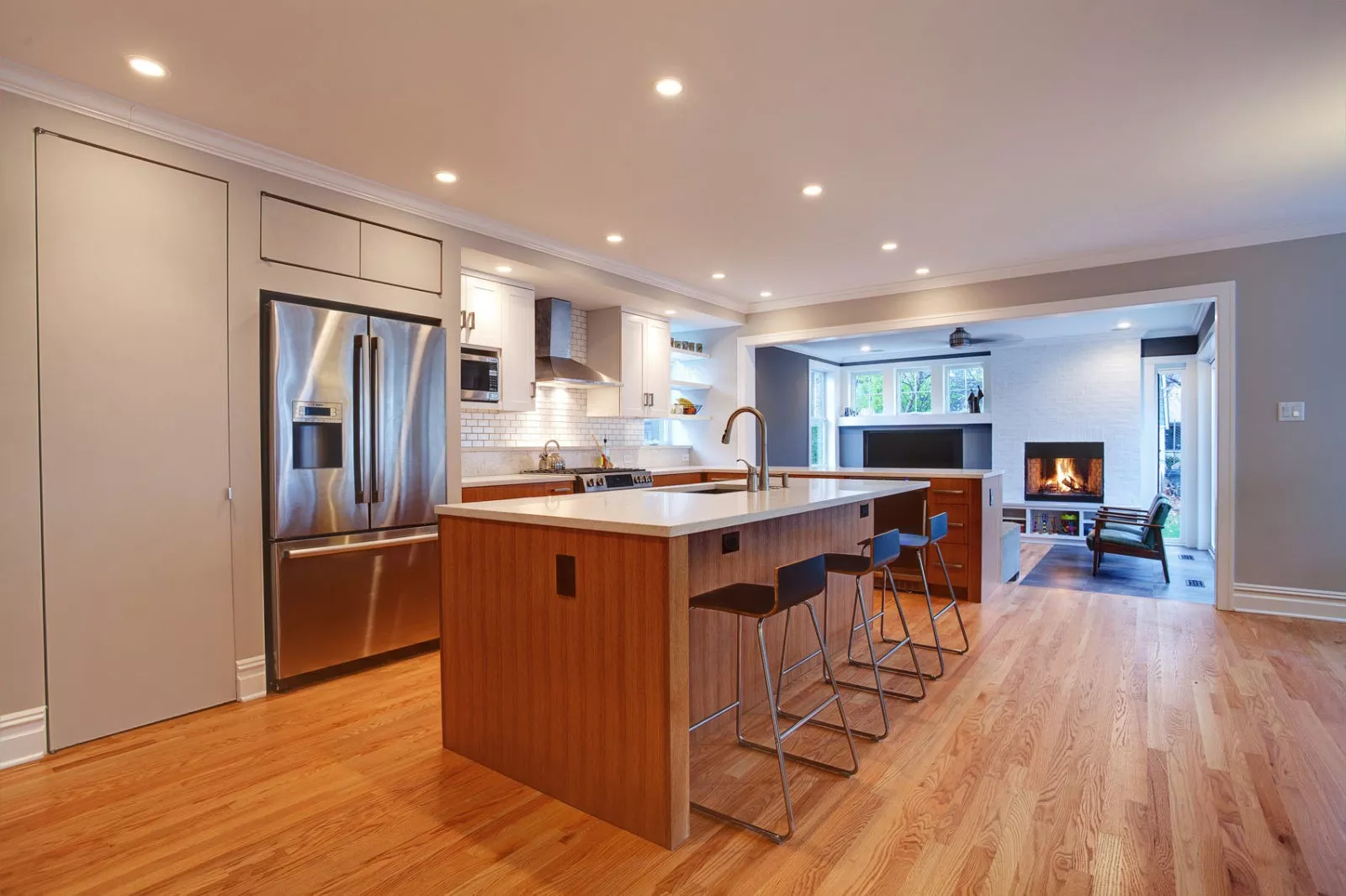 kitchen large white island hardwood floors white cabinets subway tile backsplash open to living room