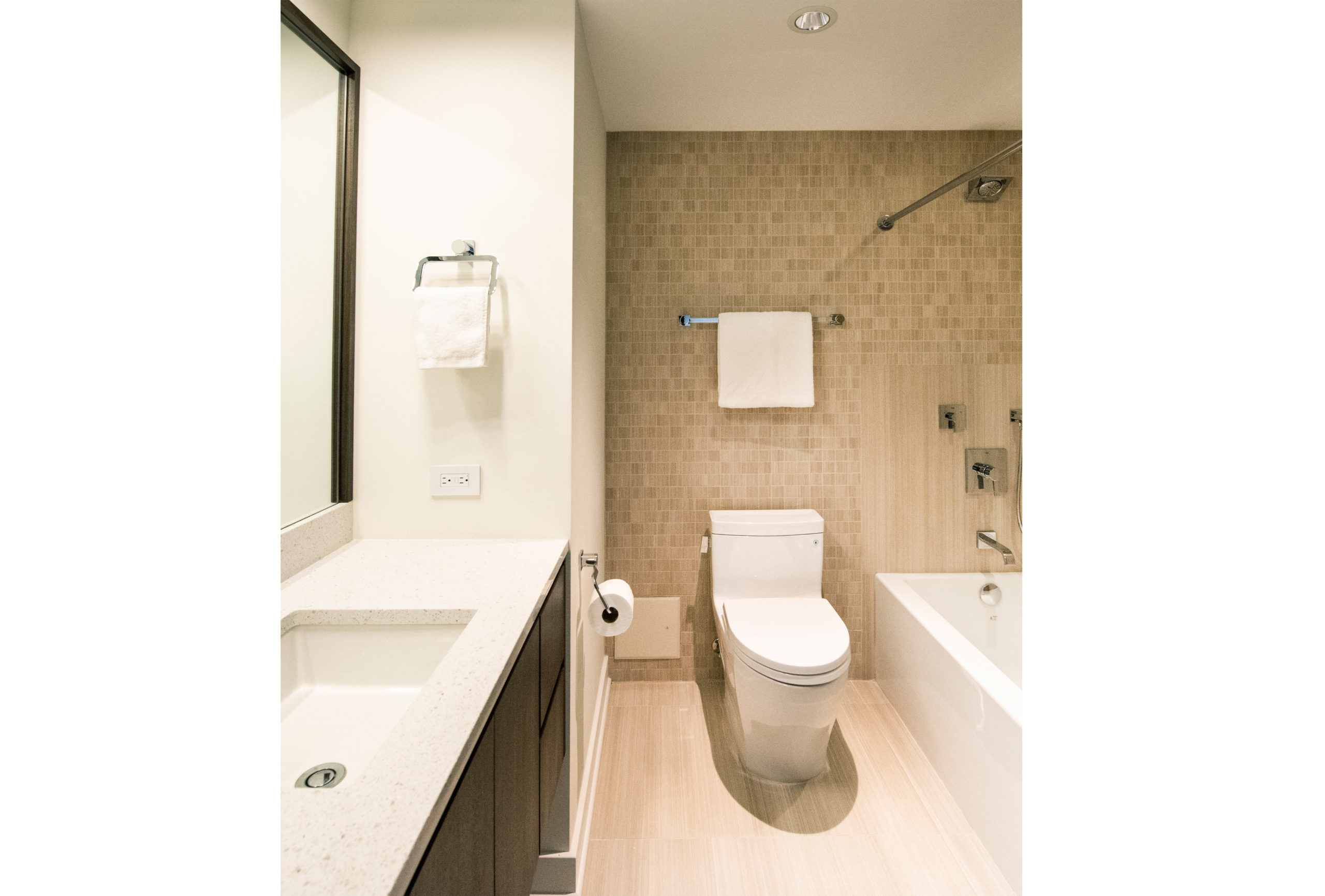 Bathroom with toilet, sink & mirror, shower, tan tile walls