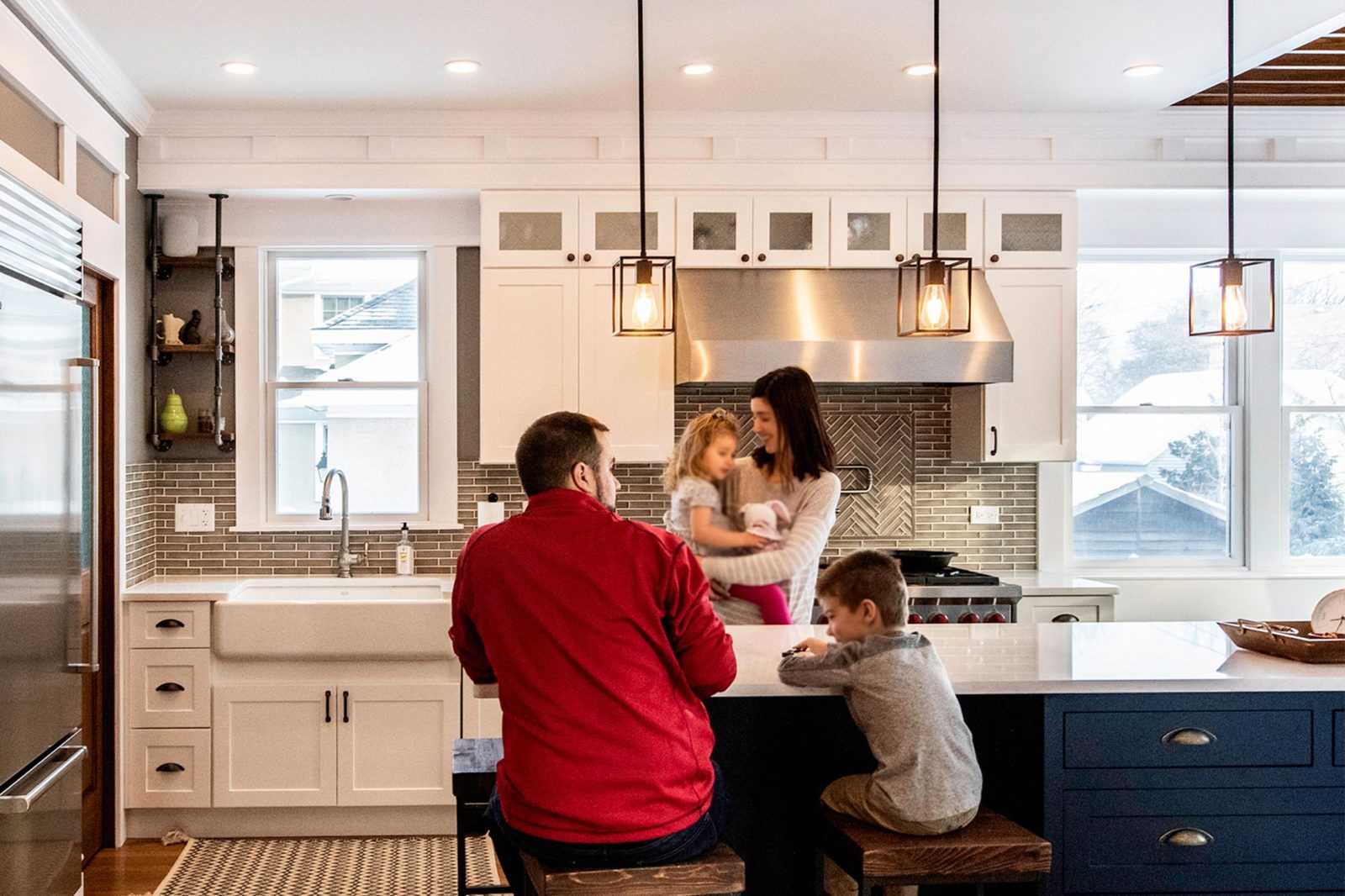 family of 4 enjoys kitchen renovation white cabinetry island with end seating square pendant lights