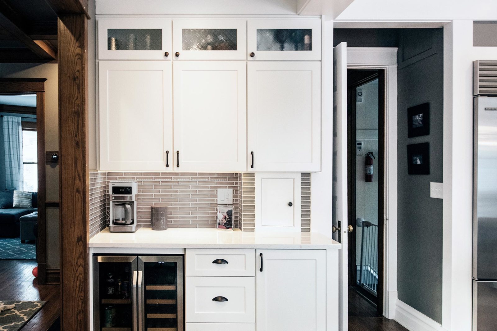 white cabinets with coffee maker on white countertops grey tile backsplash wine cooler in kitchen