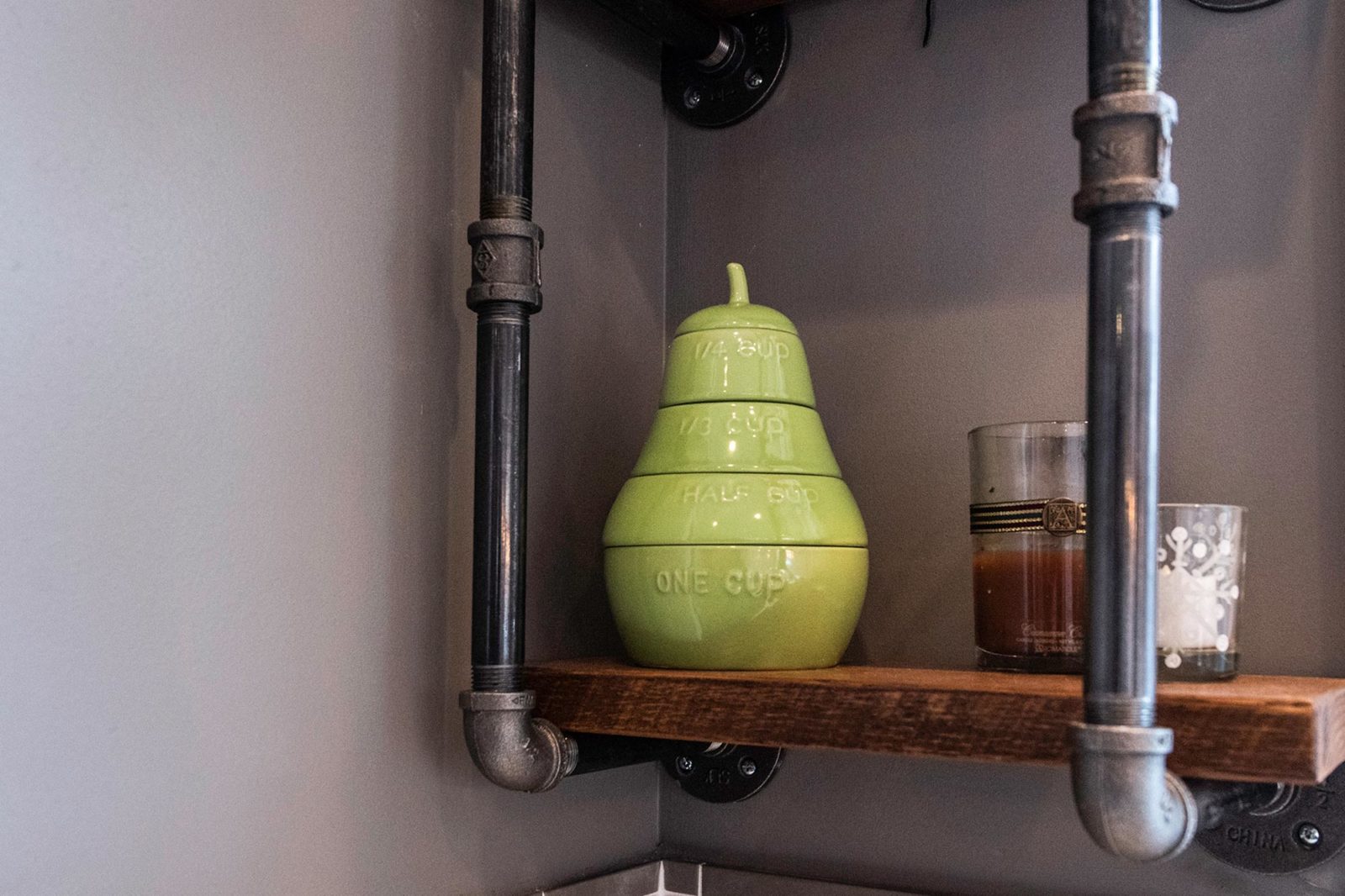 Green ceramic pear-shaped jar with measurement markings on a shelf