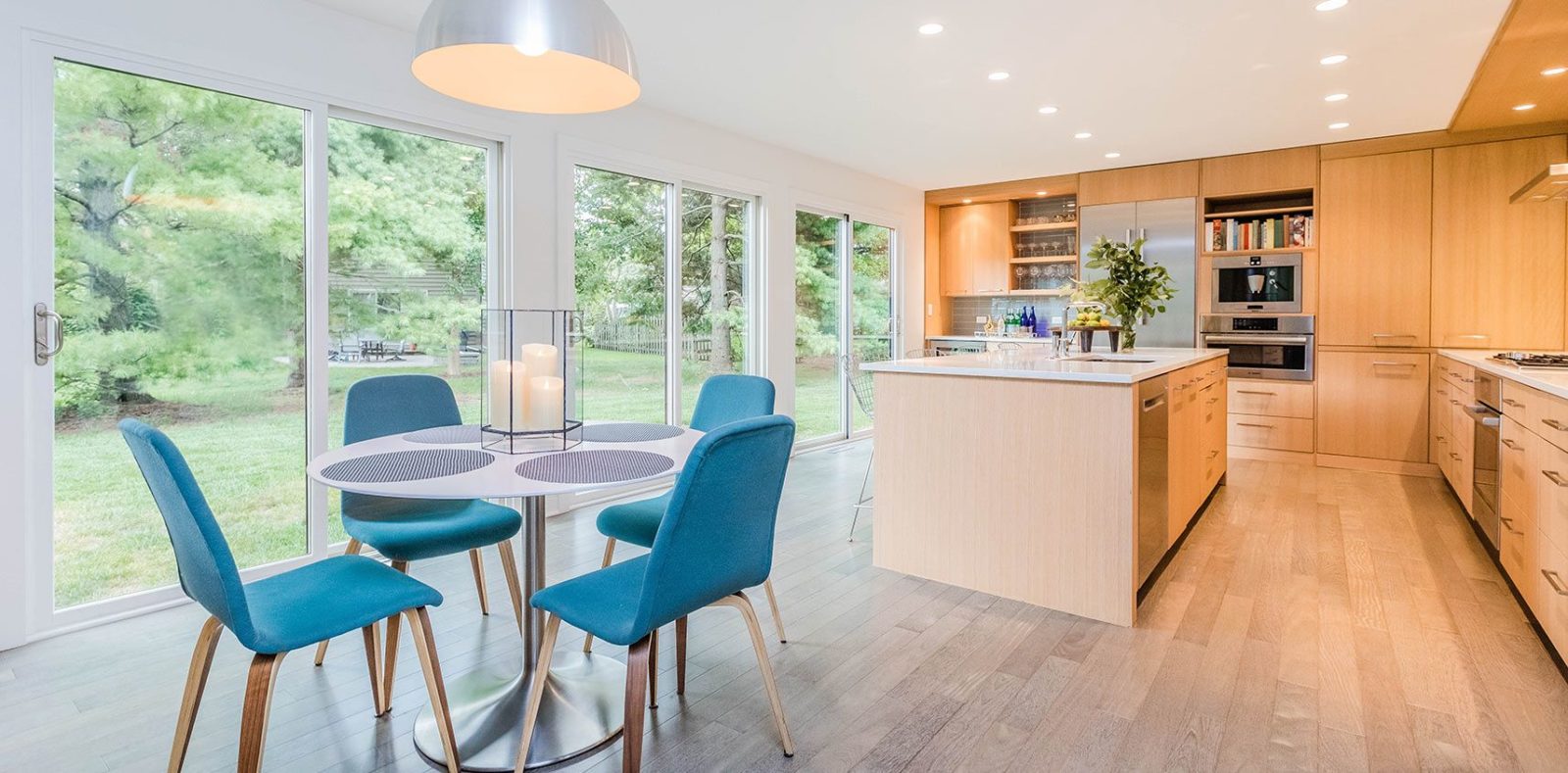 bright kitchen floor to ceiling windows light wood cabinets and large island with white countertop