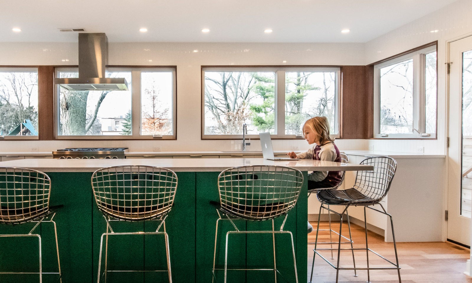 boy sitting at green island of kitchen addition