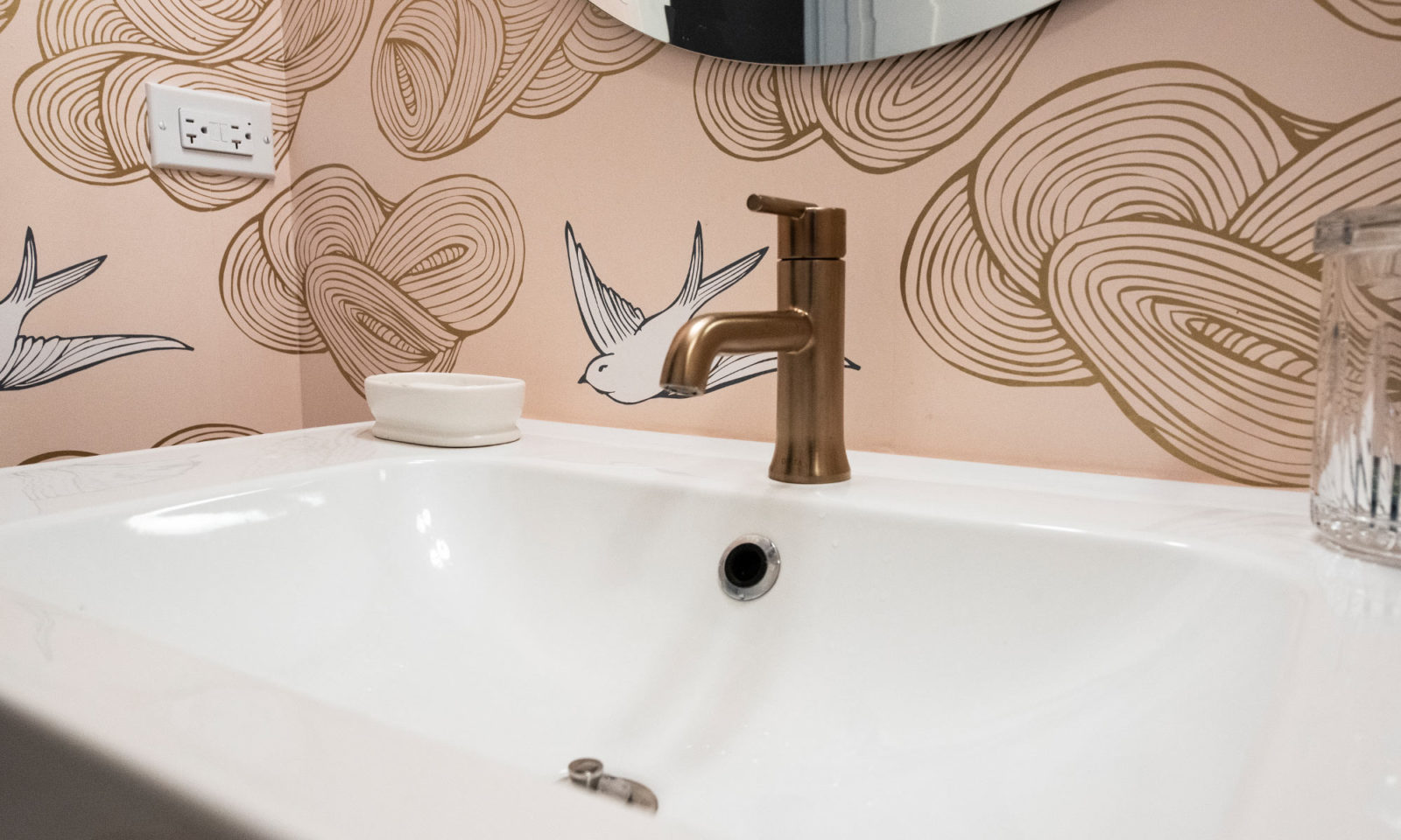 bathroom remodel showing sink and champagne faucet with pink wallpaper