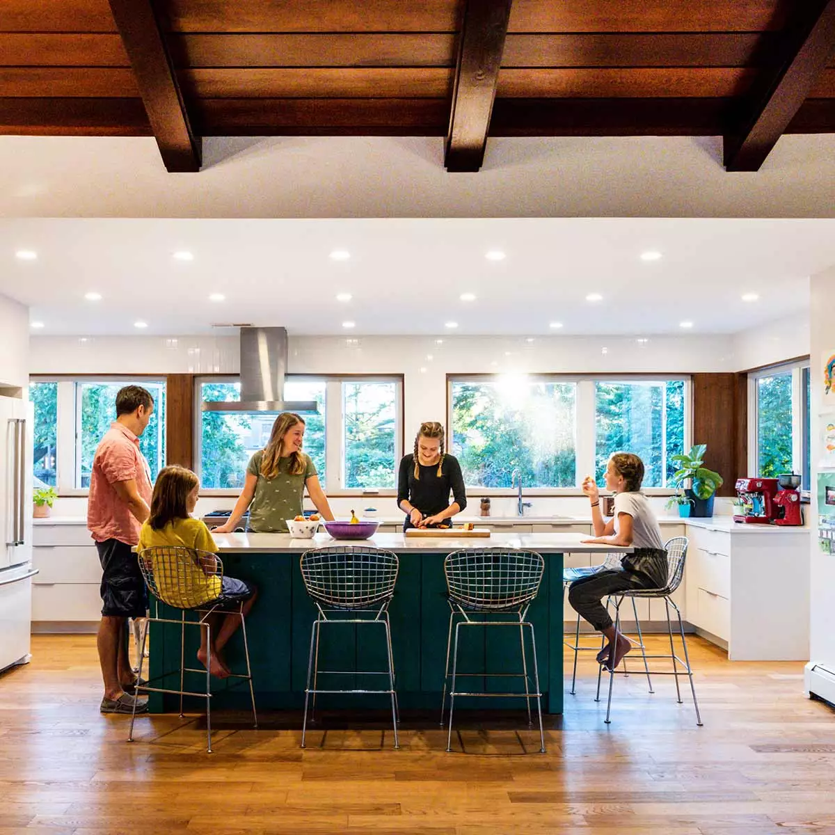 family standing around a green kitchen island in a mid century modern luxury addition
