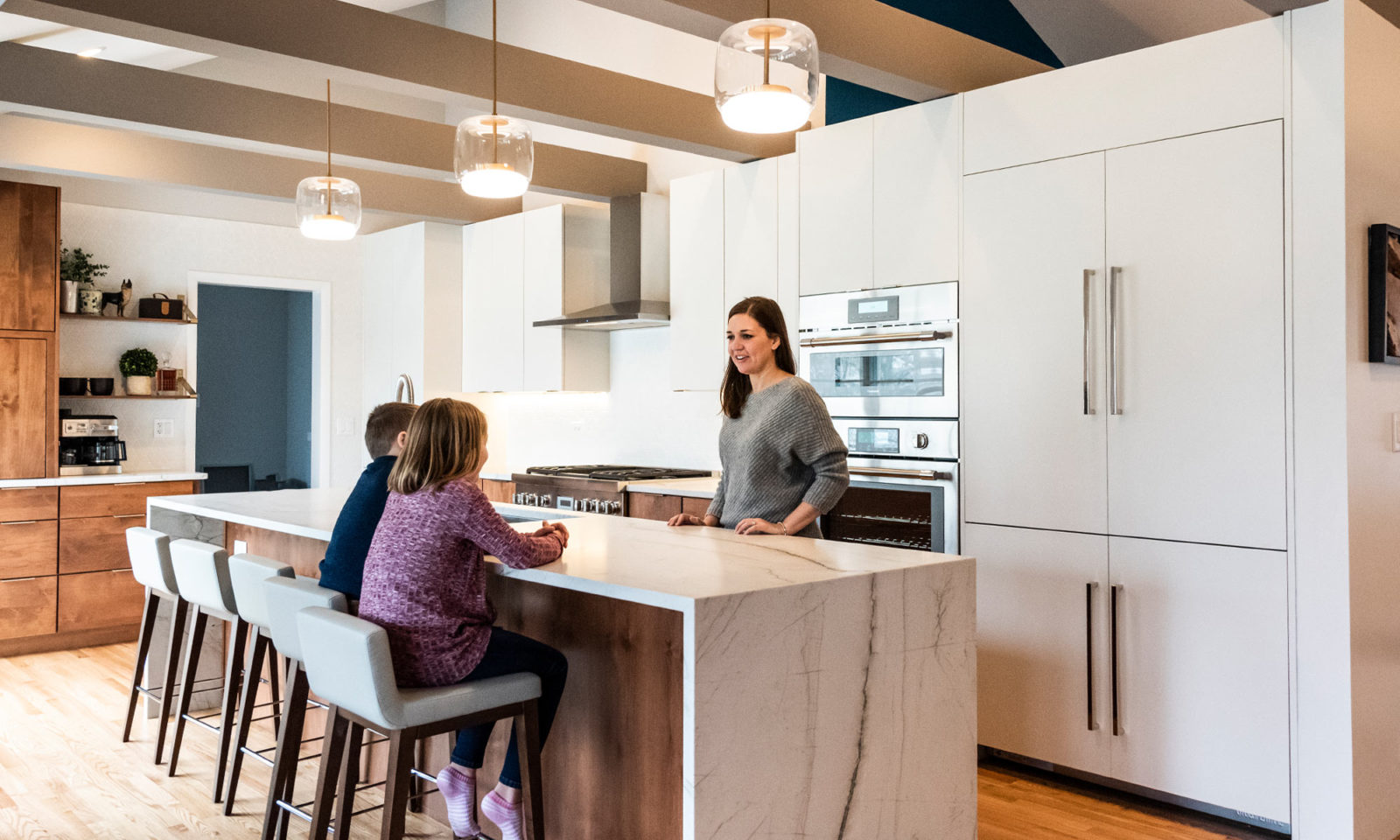 A mom and her two children convene in LivCo remodeled kitchen marble waterfall island