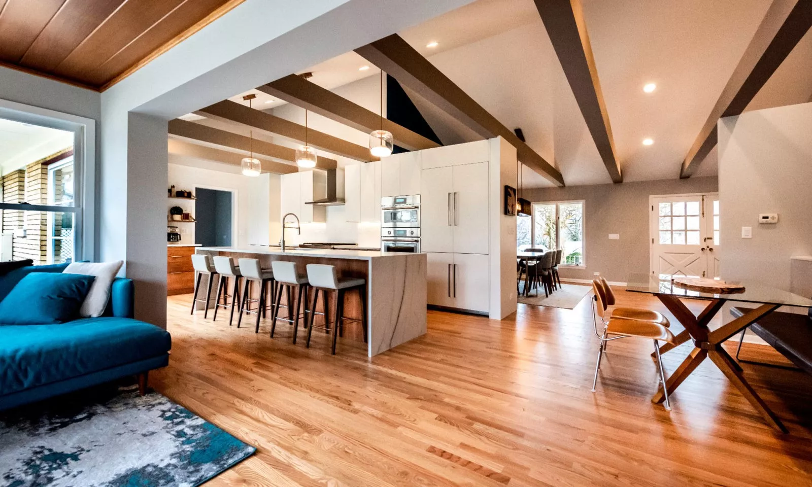 living room with blue couch leading into open kitchen with large island granite waterfall countertop