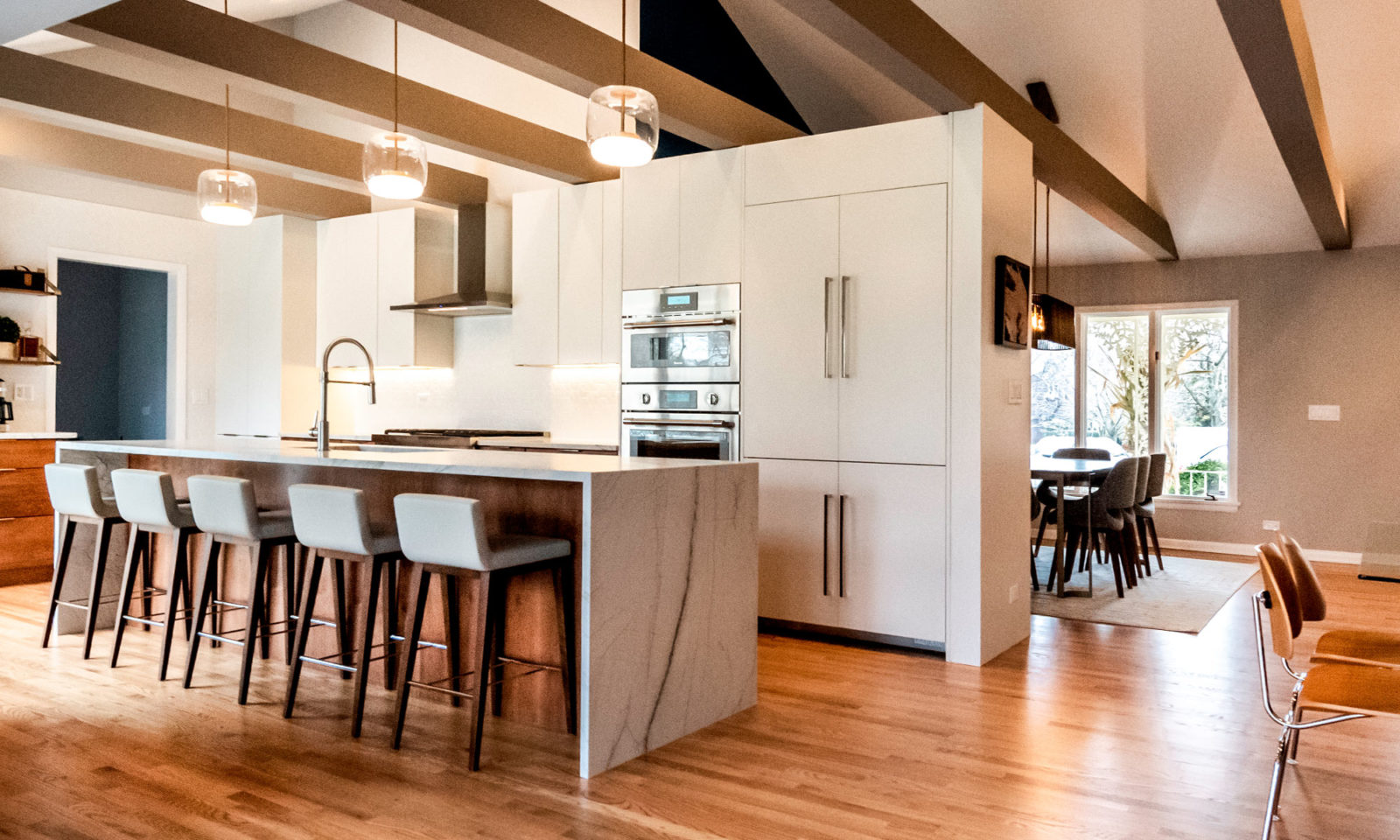 galley kitchen renovation large marble waterfall island white cabinetry and pantry double oven