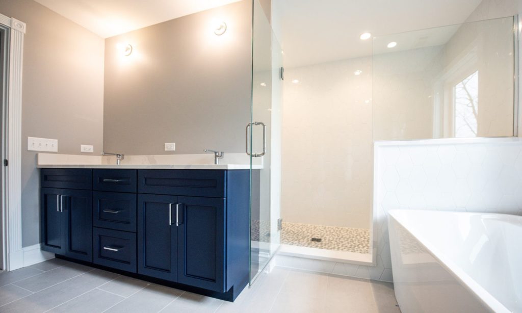 Newly renovated bathroom with new standing shower, deep bathtub, light color walls, and statement sink cabinets