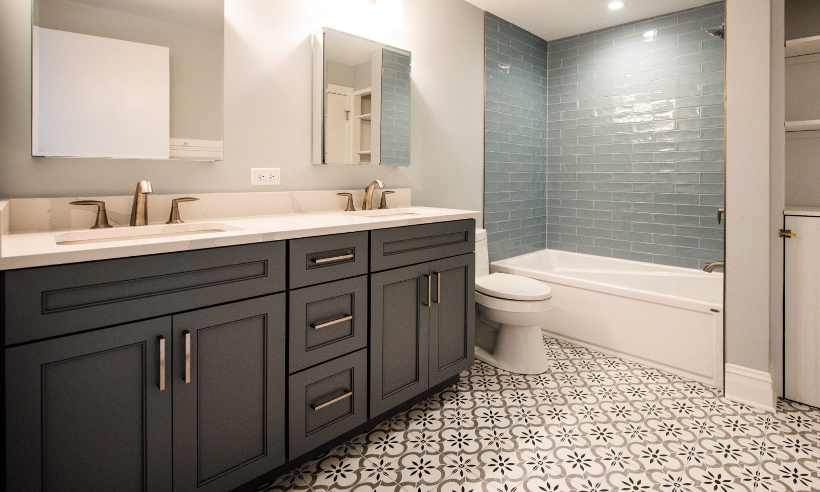 Newly renovated bathroom with designed tile flooring and statement dark sink cabinets