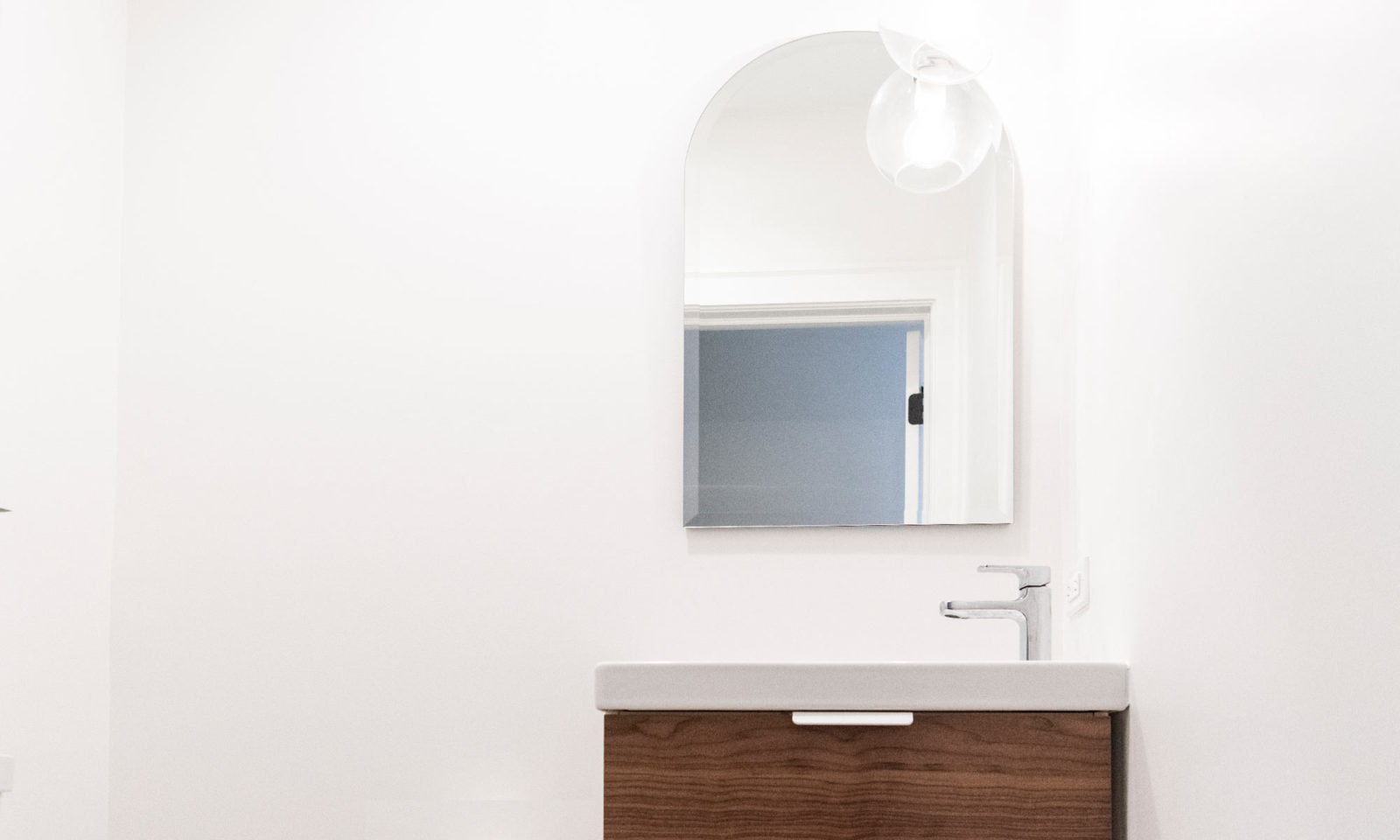 Newly renovated bathroom with white walls and dark wooden sink cabinetry