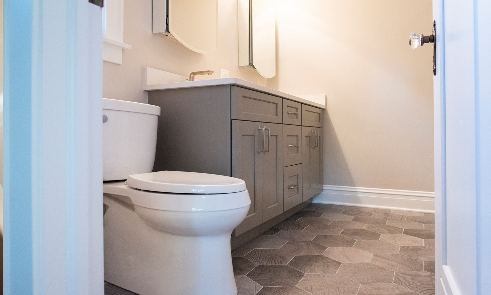 Newly renovated bathroom with gray honeycomb floor tiles and a statement gray sink cabinet
