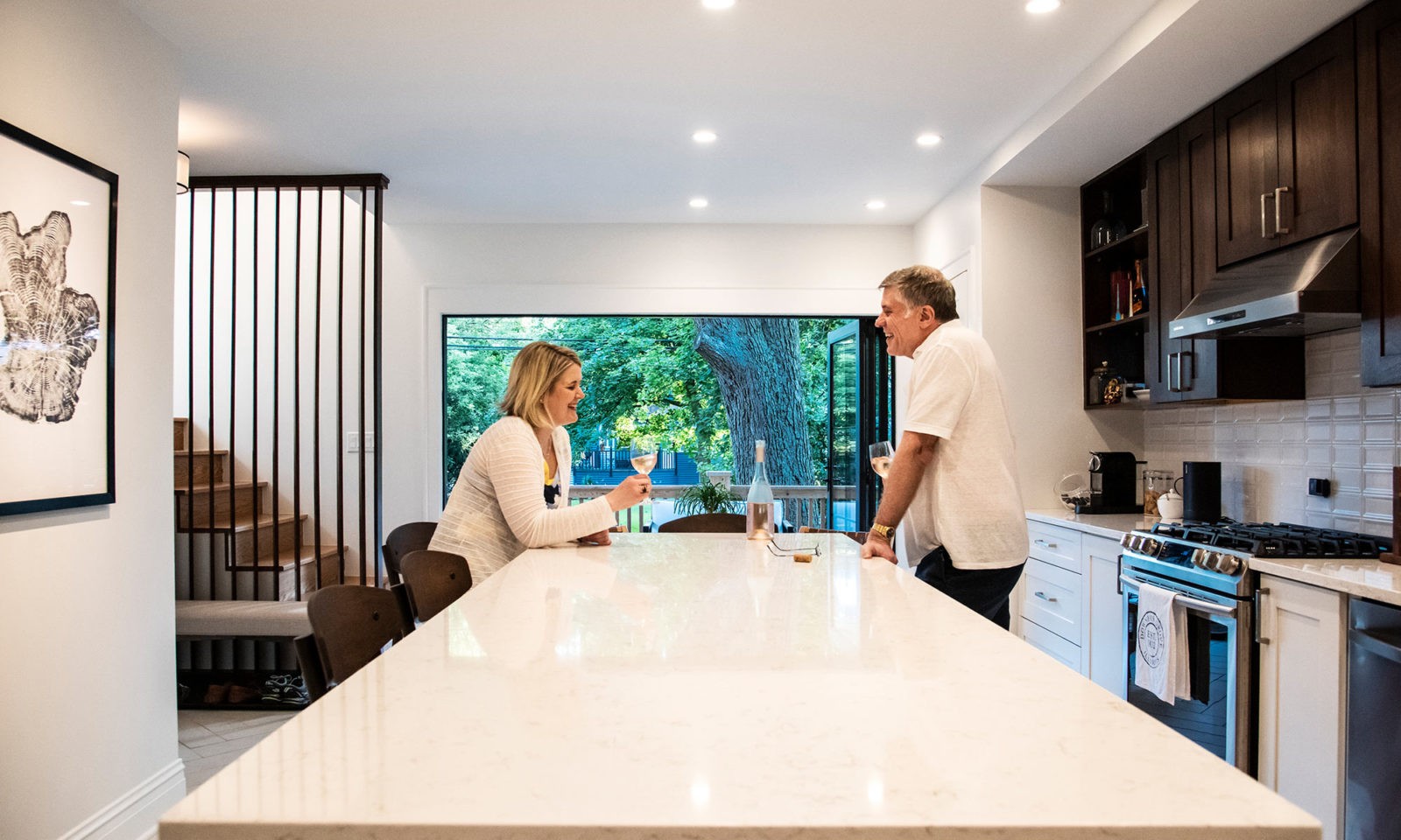 2 people drinking wine at a kitchen island in a newly renovated kitchen