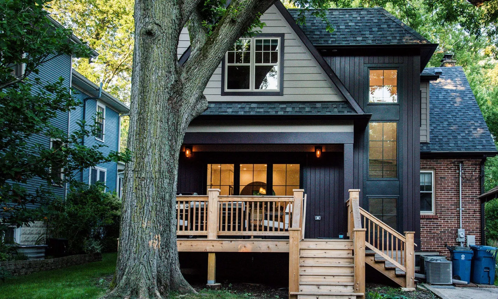 Exterior of a newly renovated home with custom porch, large glass doors, and dark design