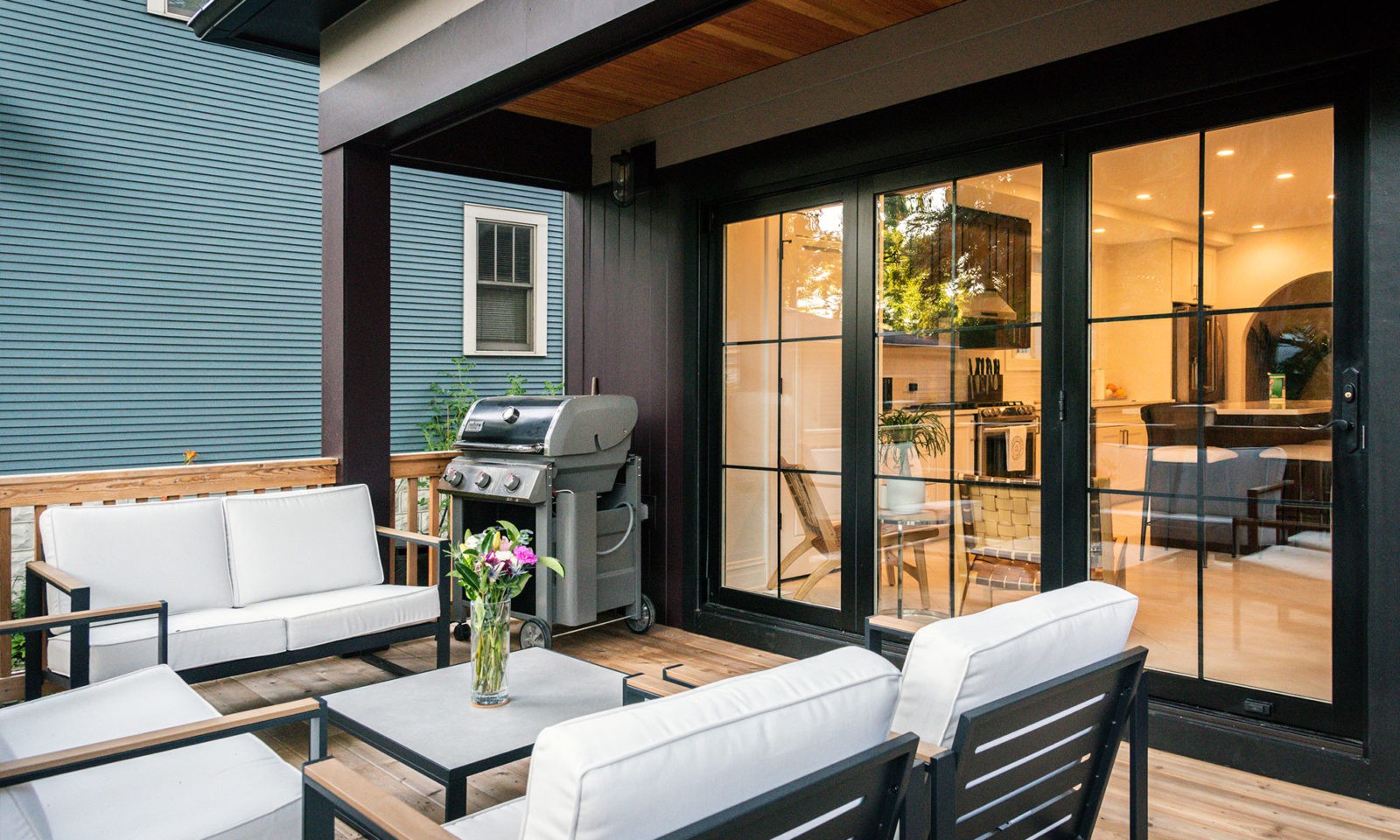 Newly renovated patio area with outdoor furniture, gas grill, and glass doors