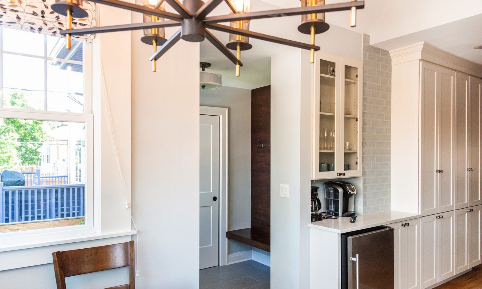 Newly renovated kitchen with wooden chandelier, glass cabinet doors, white cabinet doors, and stainless steel appliances